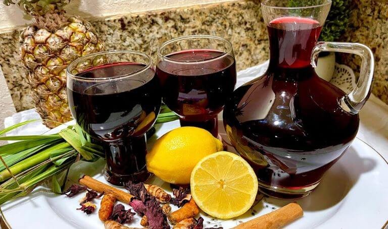 Glass of red zobo drink with ingredients