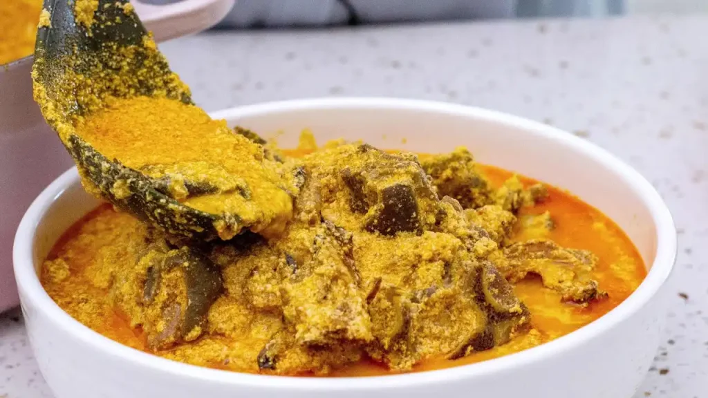 egusi soup simmering in a pot with vegetables and meat