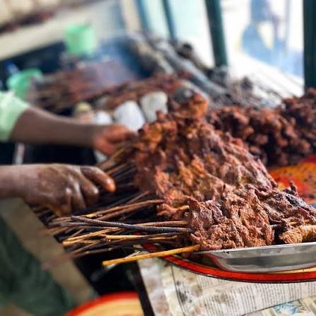 Suya skewers grilling over open flame